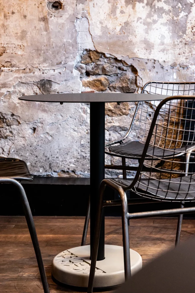 tables de bistro en béton noir avec plateau rond sur le parquet ancien d'une brasserie