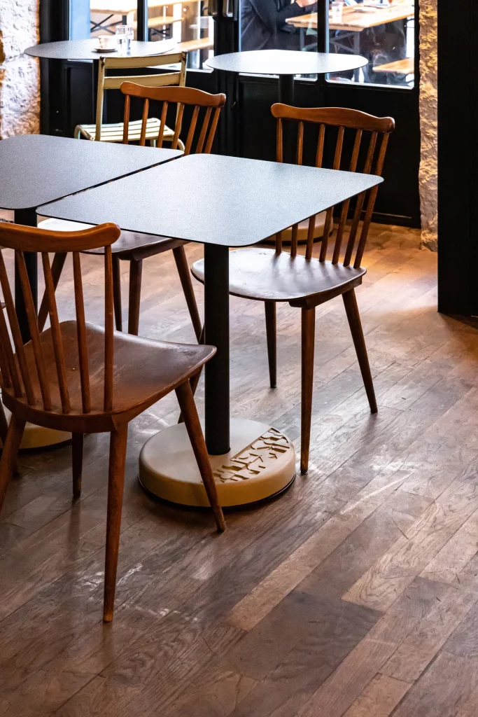 deux tables de bistro en béton rectangulaire accompagné de chaises à pied compas en bois