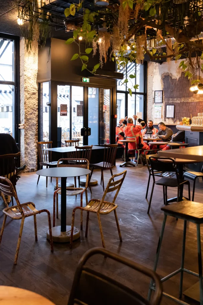 the interior of the Lyon bar "le Commerce" is equipped with round tables and square Donut tables surrounded by old metal chairs