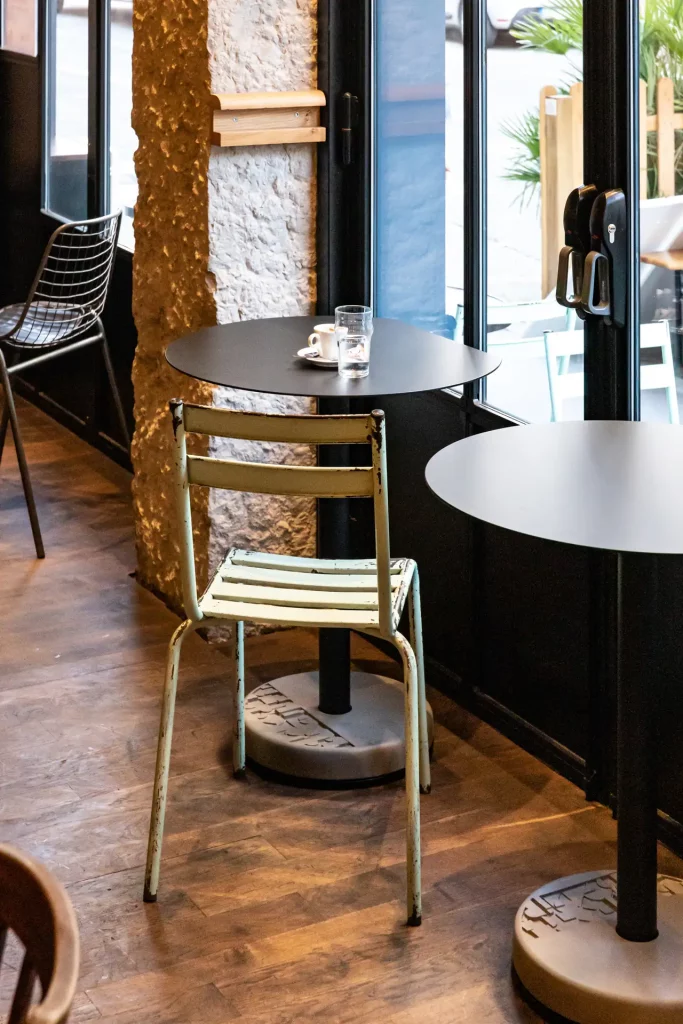 un duo de tables tronquées Donut, noir et avec leurs bases en béton sur un parquet ancien de brasserie