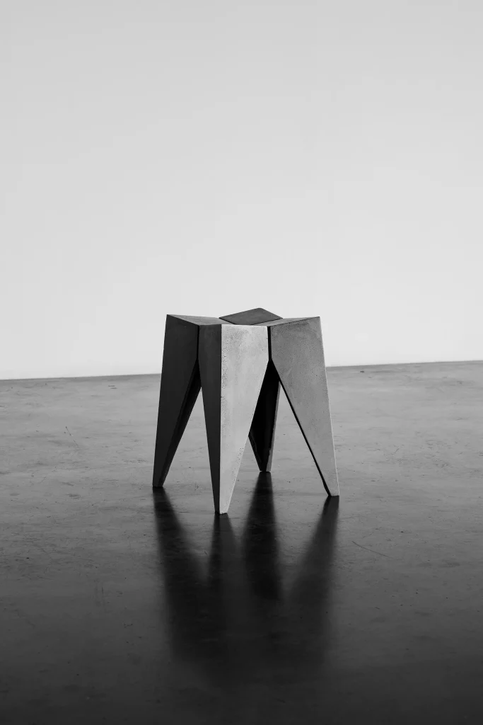 Tabouret Bridge en béton sur un sol en béton ciré, photo en noir et blanc.