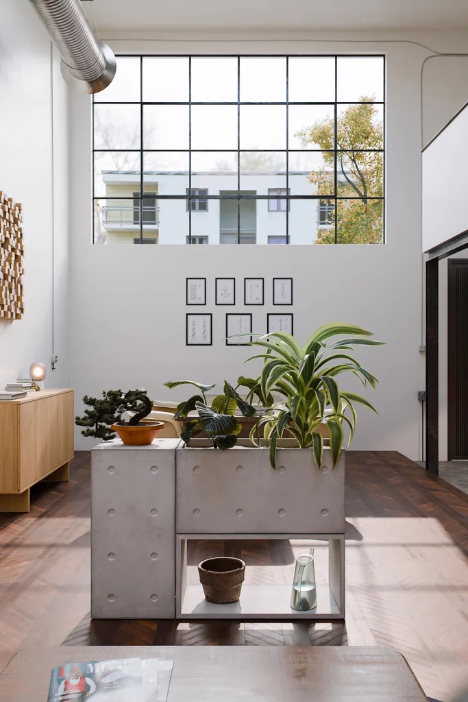 Modules Dice en béton assemblés en jardinière, avec des plantes, dans un loft sous une verrière.