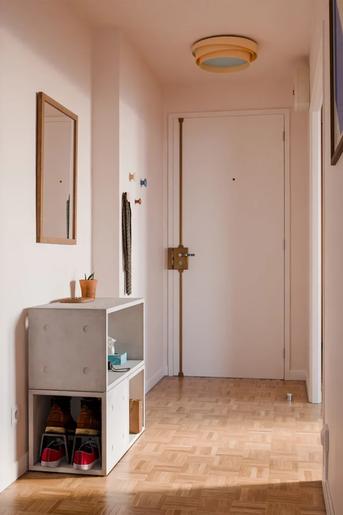 Meuble d’entrée en modules Dice en béton, avec des chaussures en bas et une plante dessus.