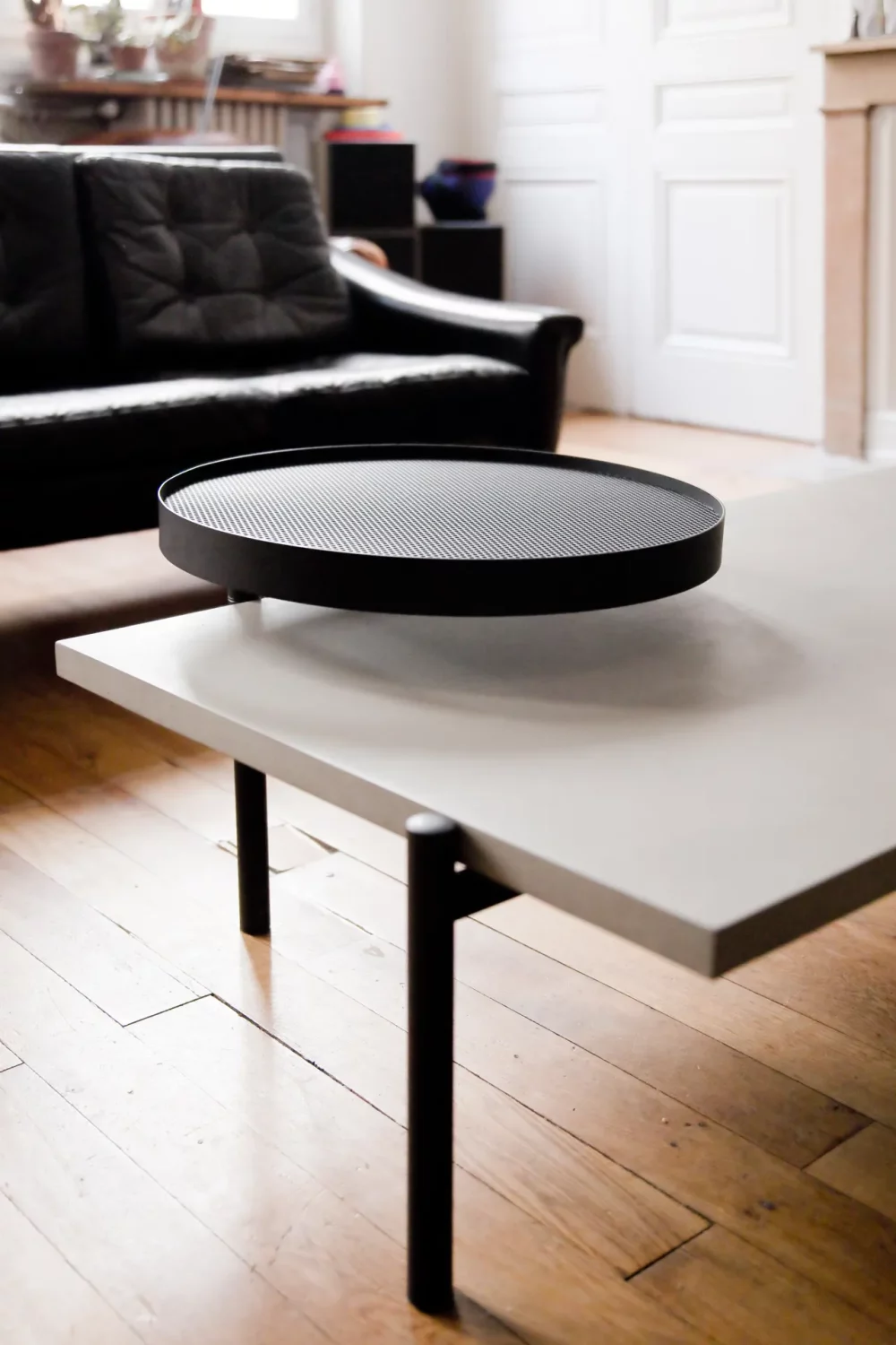 La table basse Twist avec sont plateau en béton et son second plateau en métal noir s'associe parfaitement dans un appartement haussmannien