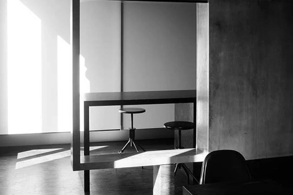 Bureau brutaliste avec un long plan de travail en béton brut, un plancher en bois et une verrière inclinée