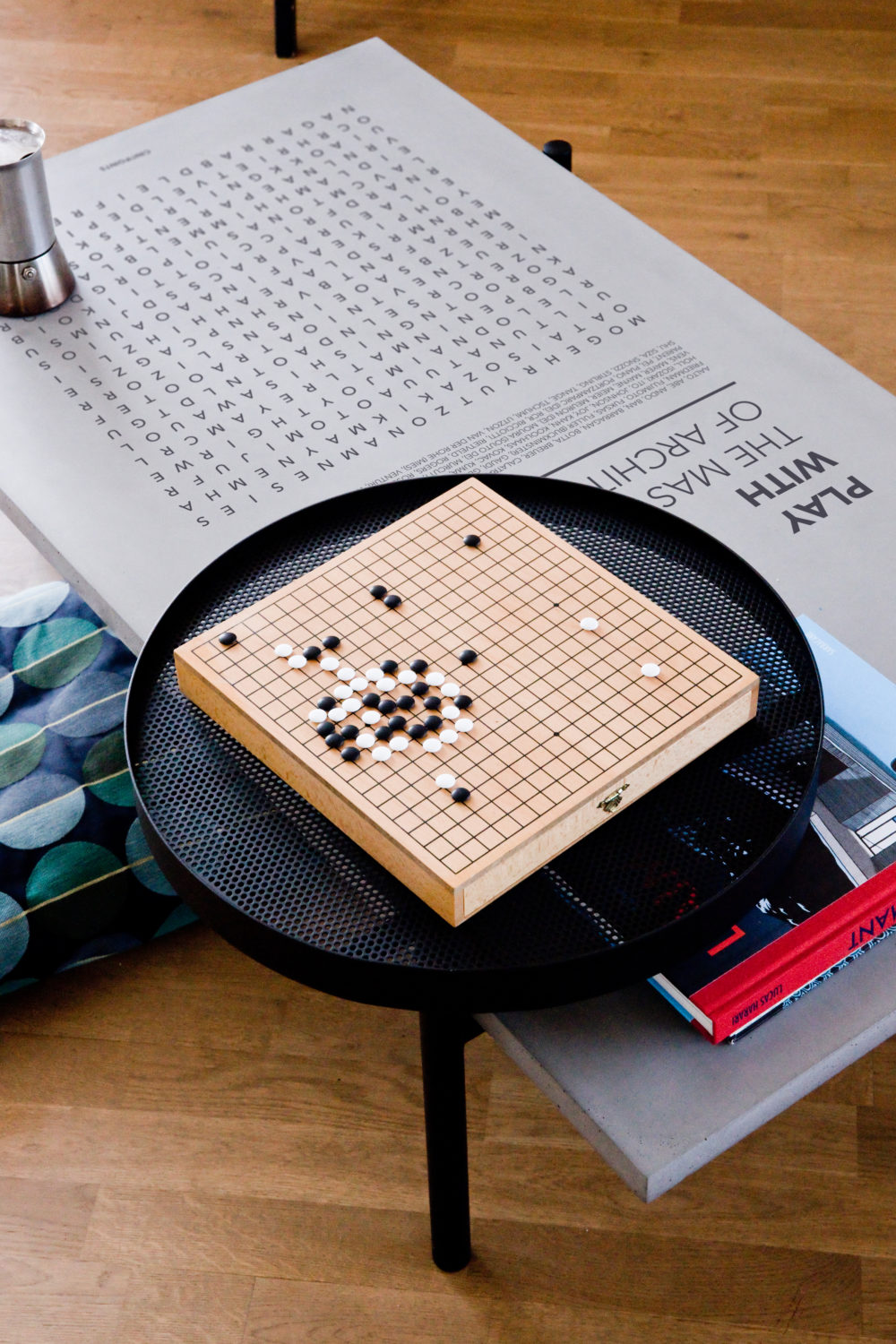 Notre table basse Twist avec son plateau en métal noir accessoirisé d'un jeu de Go