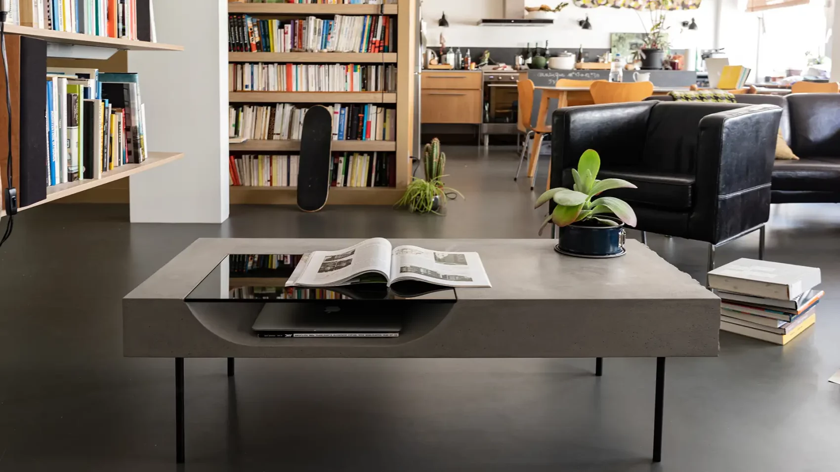 Table basse en béton dans un loft avec bibliothèque, fauteuil en cuir noir et parquet — Lyon Béton